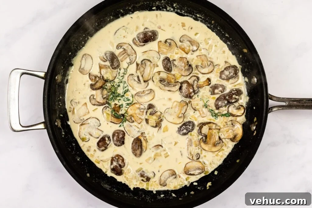 Creamy Garlic Mushroom Pasta Recipe — Quick Weeknight Comfort 7 Creamy mushroom sauce reducing in a skillet.