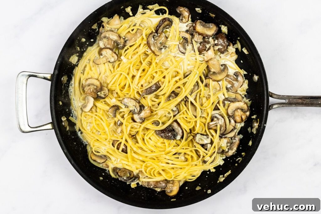 Creamy Garlic Mushroom Pasta Recipe — Quick Weeknight Comfort 8 Creamy garlic mushroom pasta cooking in a skillet.