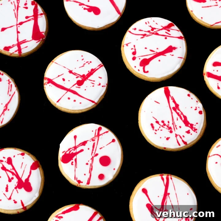 Flat lay view of lots of blood spatter halloween cookies lay on a black backdrop.