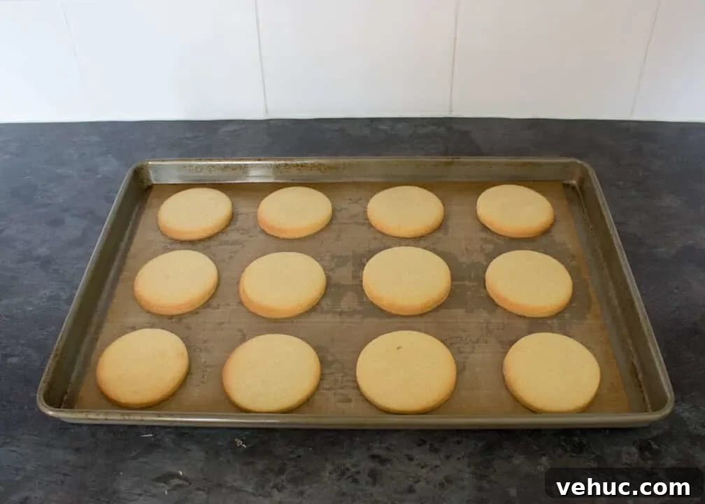 Blood-Spattered Halloween Cookie Ideas for a Spooky Party 23 Baked cookies on a lined baking tray on a kitchen worktop.