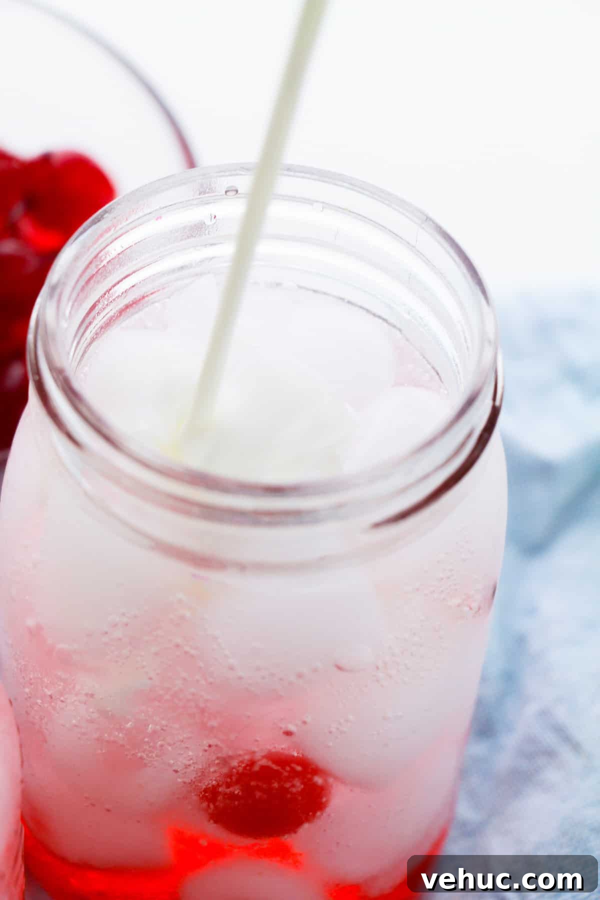Shirley Temple Dirty Soda Recipe — Sparkling Cherry Lime Mocktail 5 Creamer being poured into mason jar.