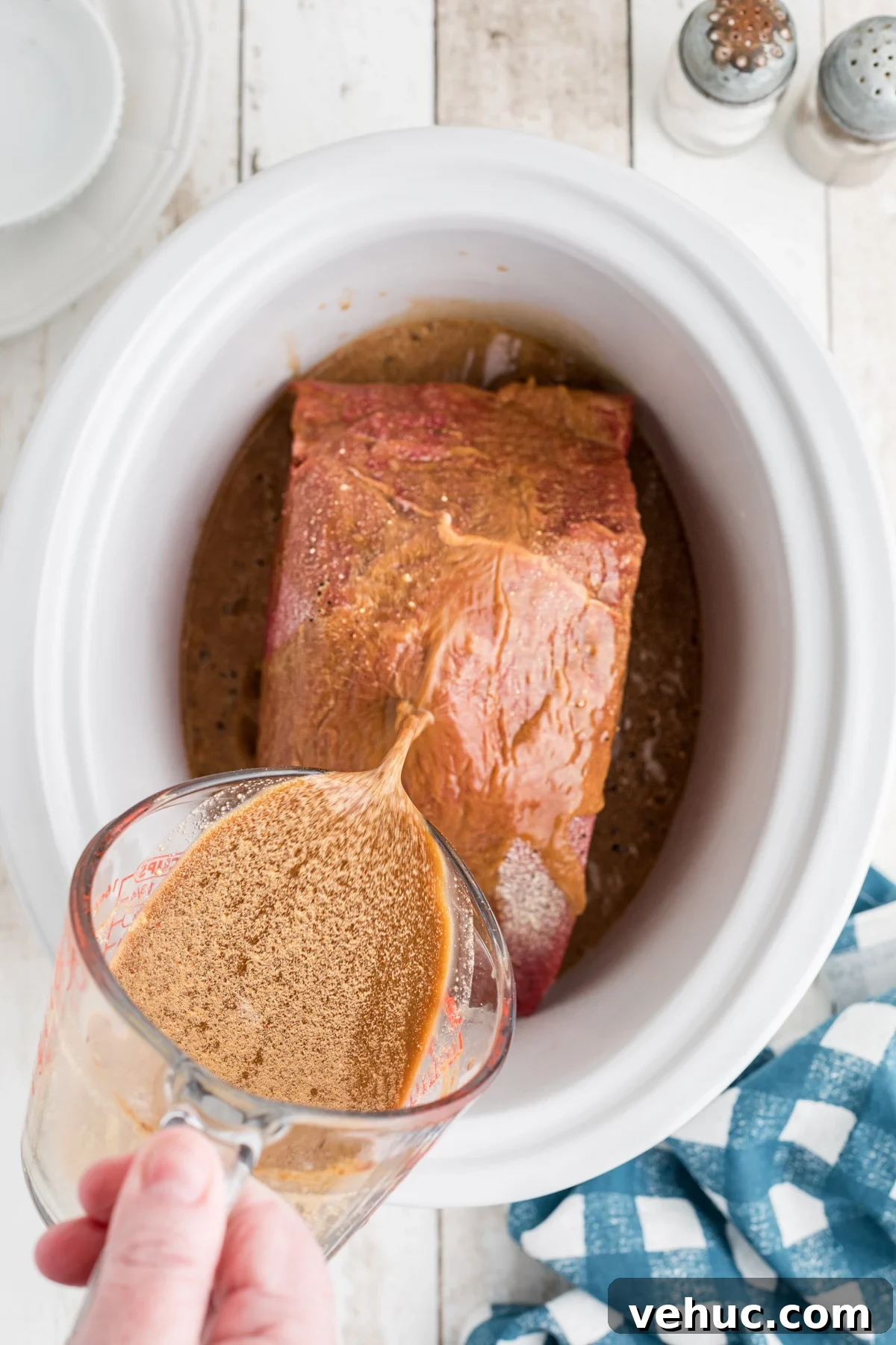 gravy mix being poured over roast in slow cooker.