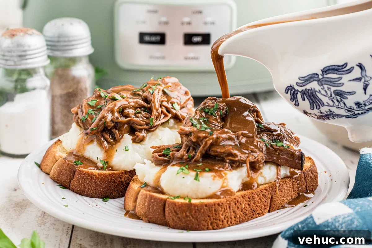Gravy being pour over a hot roast beef sandwich.