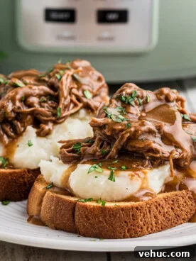 2 hot roast beef sandwiches on a plate.