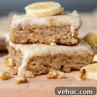 Gluten-Free Banana Bars with Creamy Frosting 9 a stack of two banana bars with a sliced banana piece on top