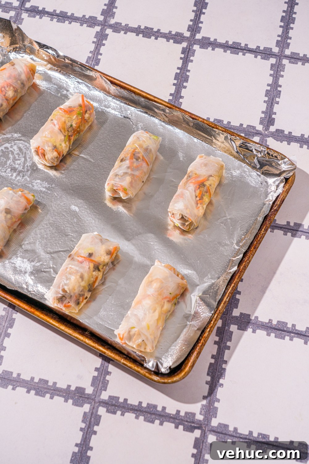 Crispy Rice Paper Veggie Dumplings: Viral TikTok Recipe 9 A baking sheet lined with foil with several rice paper veggie dumplings. The sheet is on a tiled counter.