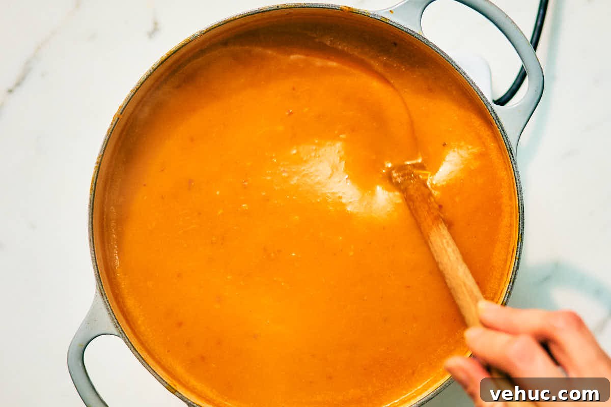 Creamy Kabocha Squash and Coconut Milk Soup — No Blender Needed 11 Creamy kabocha squash soup with coconut milk being stirred in a pot.