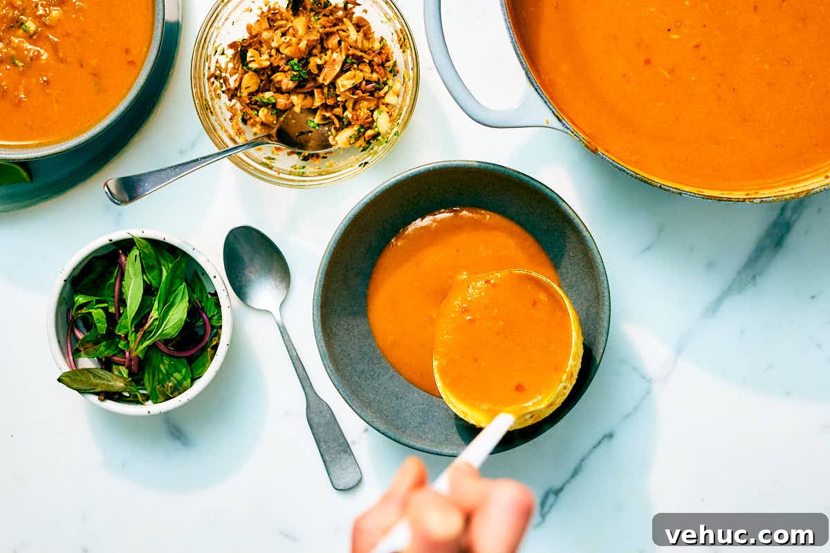 Creamy Kabocha Squash and Coconut Milk Soup — No Blender Needed 12 Kabocha Squash Soup being ladled into bowls on a marble counter.