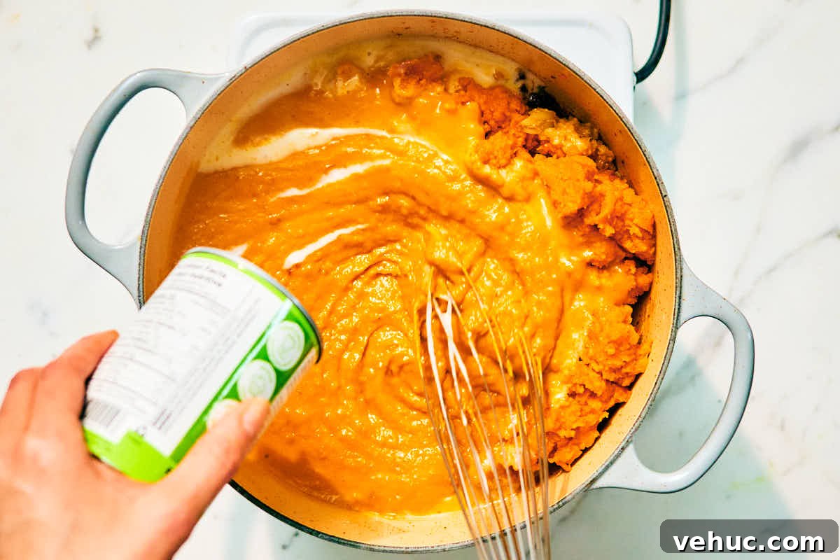 Creamy Kabocha Squash and Coconut Milk Soup — No Blender Needed 10 Coconut milk being garlic, and curry paste in a pot.