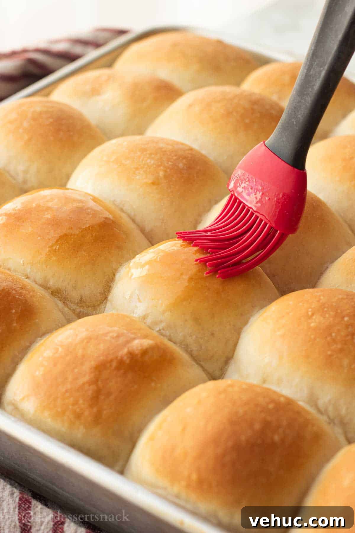 Classic Old-Fashioned Yeast Rolls Recipe 11 Red brush with melted butter over baked fluffy dinner rolls.