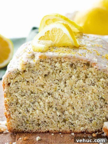 Baked lemon zucchini poppyseed loaf sliced on a wood cutting board.