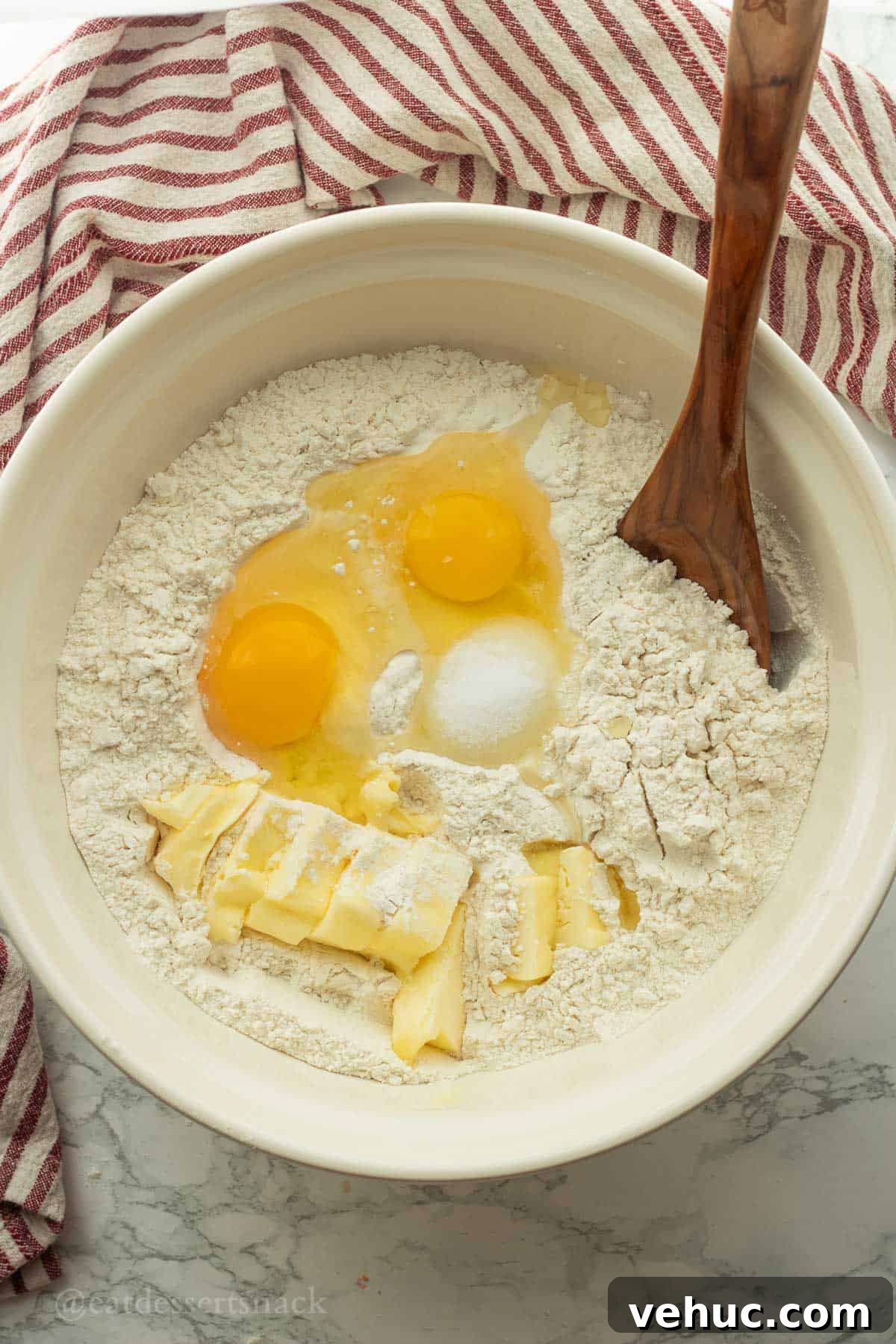 Classic Old-Fashioned Yeast Rolls Recipe 5 Soft butter, eggs, flour, and salt in white mixing bowl with wooden spoon.