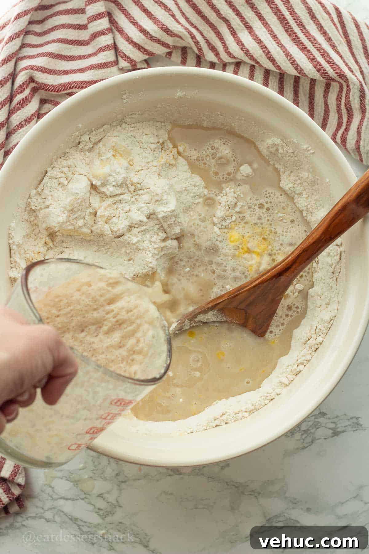 Classic Old-Fashioned Yeast Rolls Recipe 6 Yeast and water being poured into white bowl with flour, butter, and eggs.