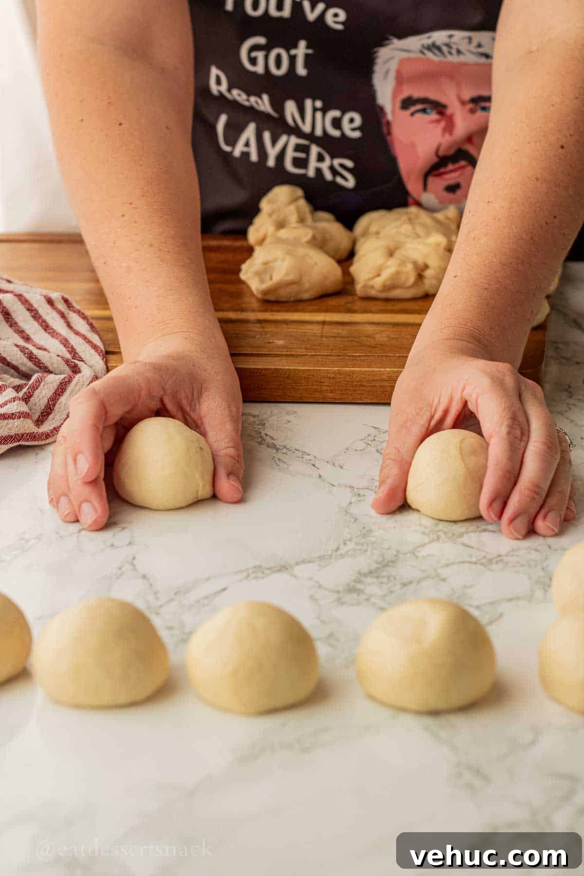 Classic Old-Fashioned Yeast Rolls Recipe 8 Rolling raw dinner roll dough portions into round balls with both hands on marble surface.