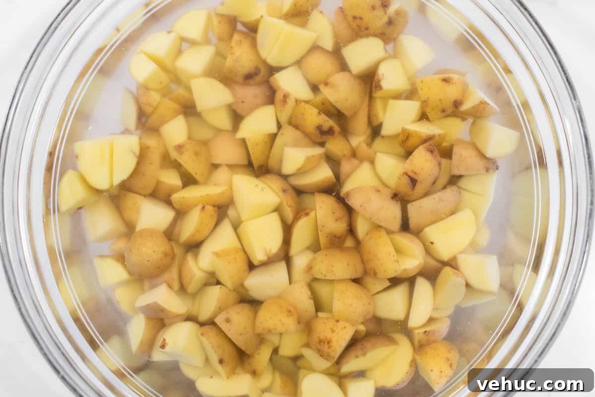 Diced potatoes soaking in water in glass bowl.