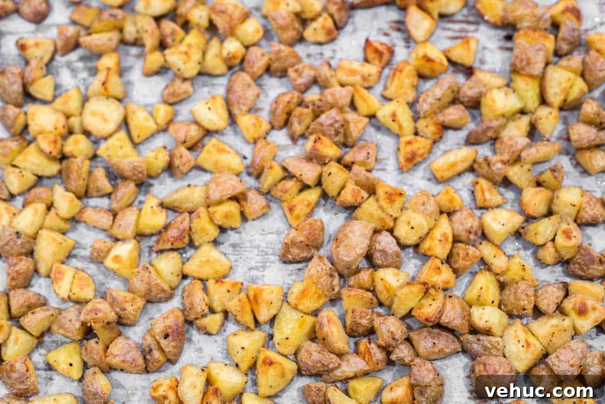Crispy roasted potatoes on parchment-lined baking sheet.