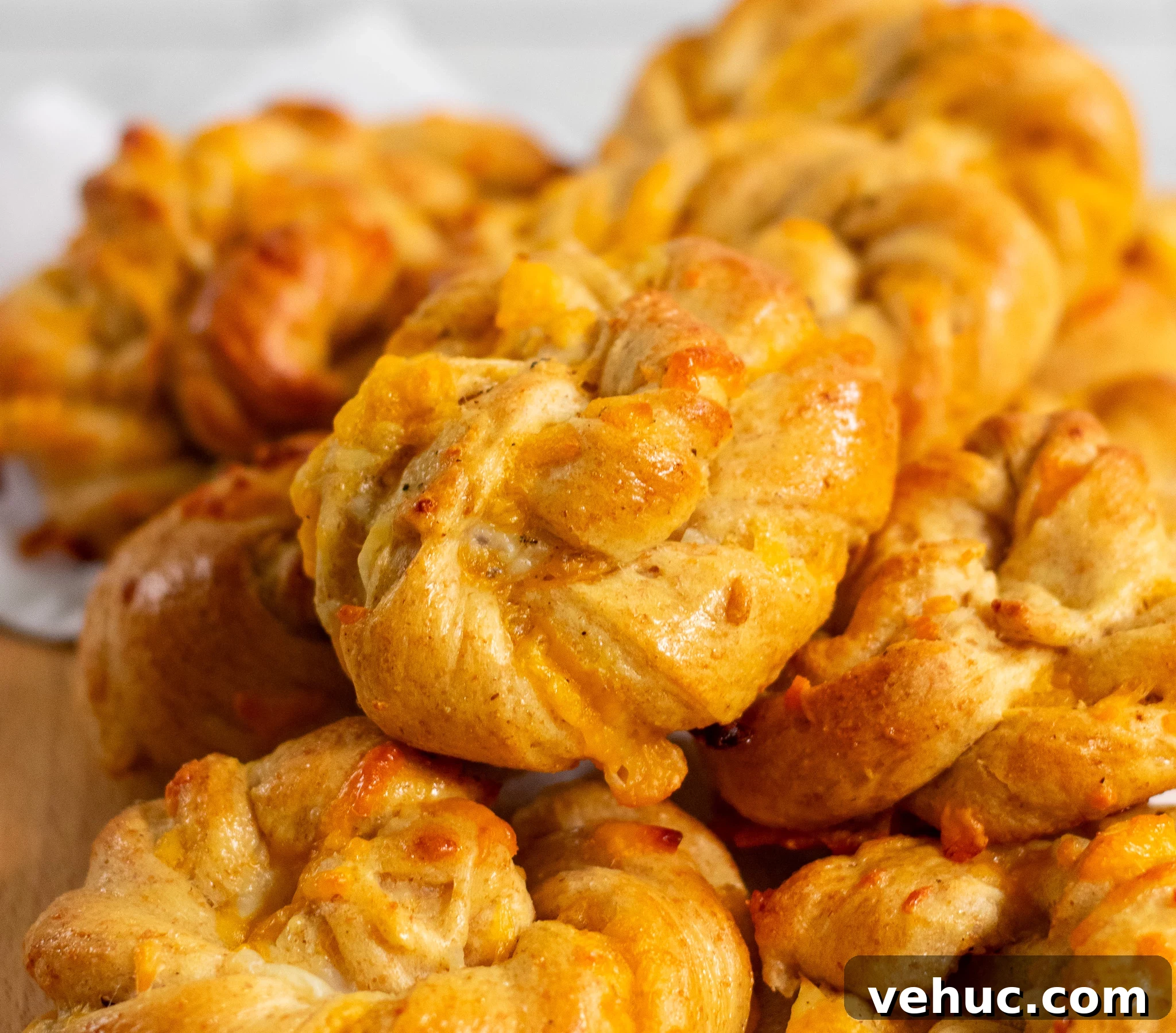 Cheese twist buns in a pile on a cutting board.