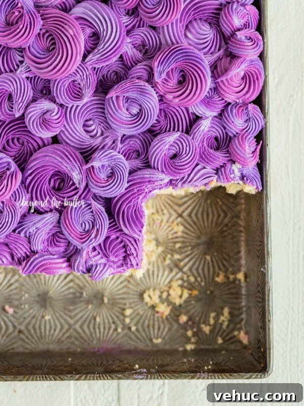 Classic Four-Egg Yellow Sheet Cake with Chocolate Frosting 10 Purple coconut frosted coconut sheet cake with slices removed in cake pan on white wood table.
