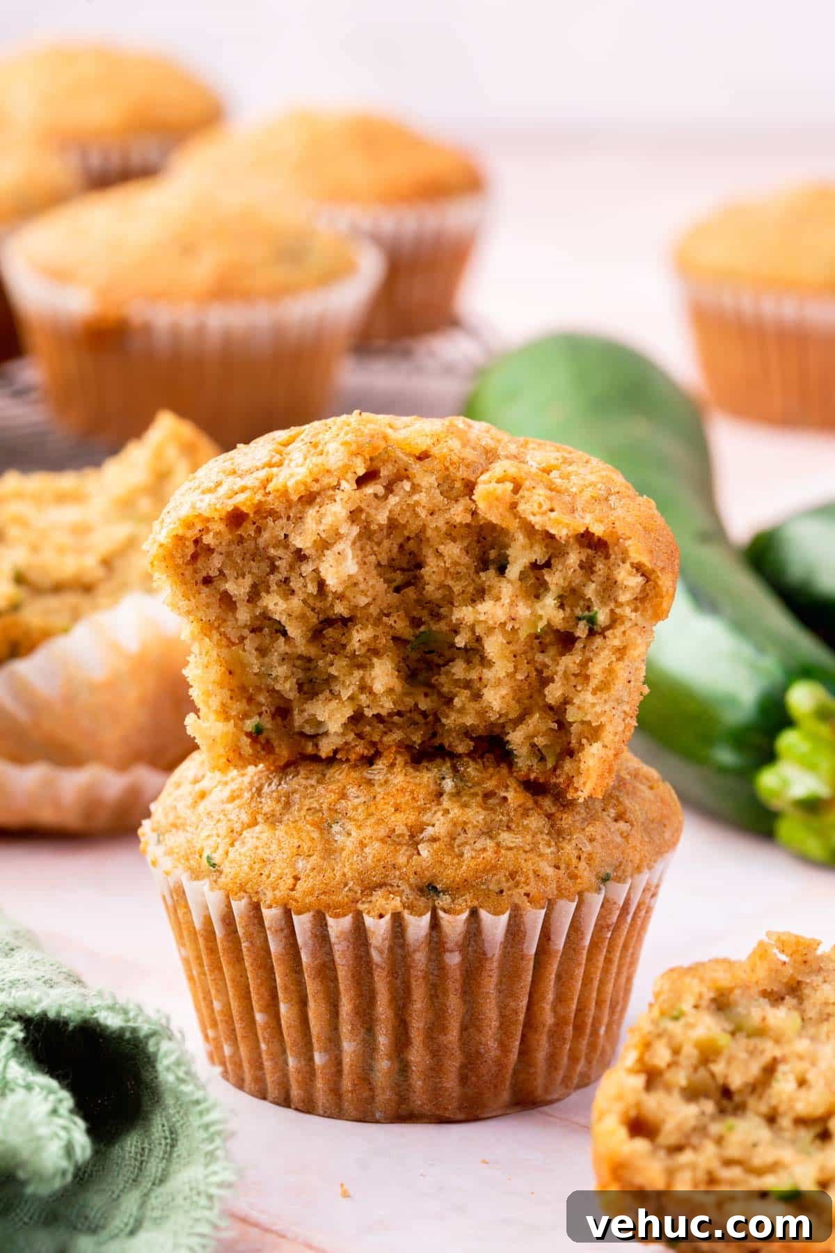 Moist Gluten-Free Zucchini Muffins with Cinnamon Oil-Free Option 11 A gluten-free zucchini muffin with a bite taken out of it stacked on top of another zucchini muffin.