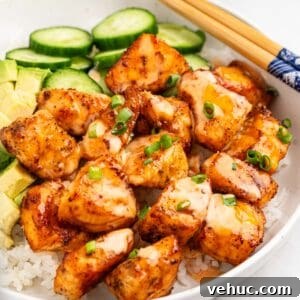 Crispy Air Fryer Salmon Bites with Lemon Garlic Dip 10 plate of air fryer salmon bites on bed of rice with slices of cucumbers and avocado.