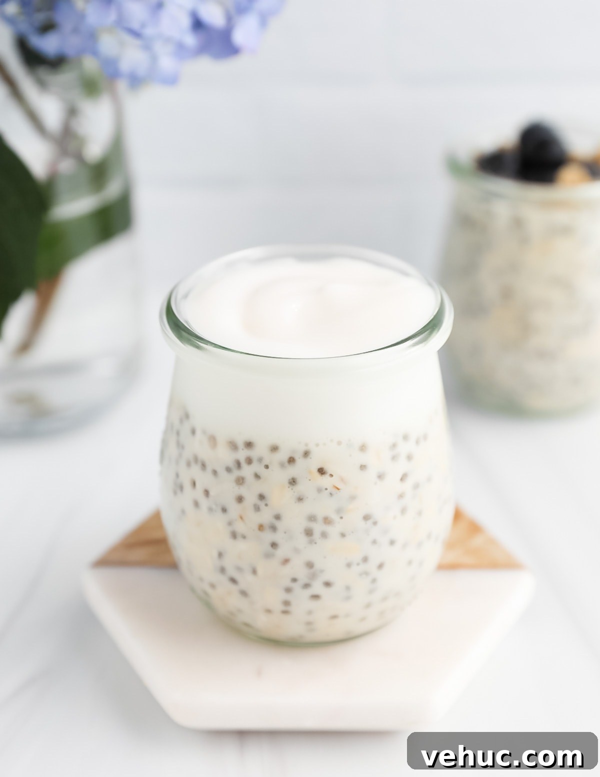 Creamy Vanilla Overnight Oats Recipe for Busy Mornings 6 A clear jar of overnight oatmeal and yogurt sitting on a coaster.