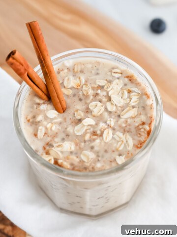 A jar of overnight oats and cinnamon sticks in the oats.