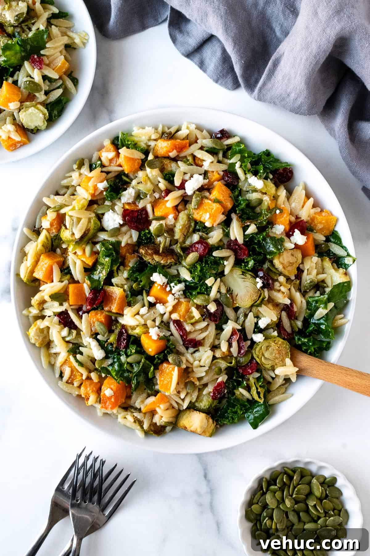 Autumn Harvest Orzo Salad with Roasted Vegetables and Feta 2 Fall Orzo Salad in a white serving bowl with a wooden spoon.