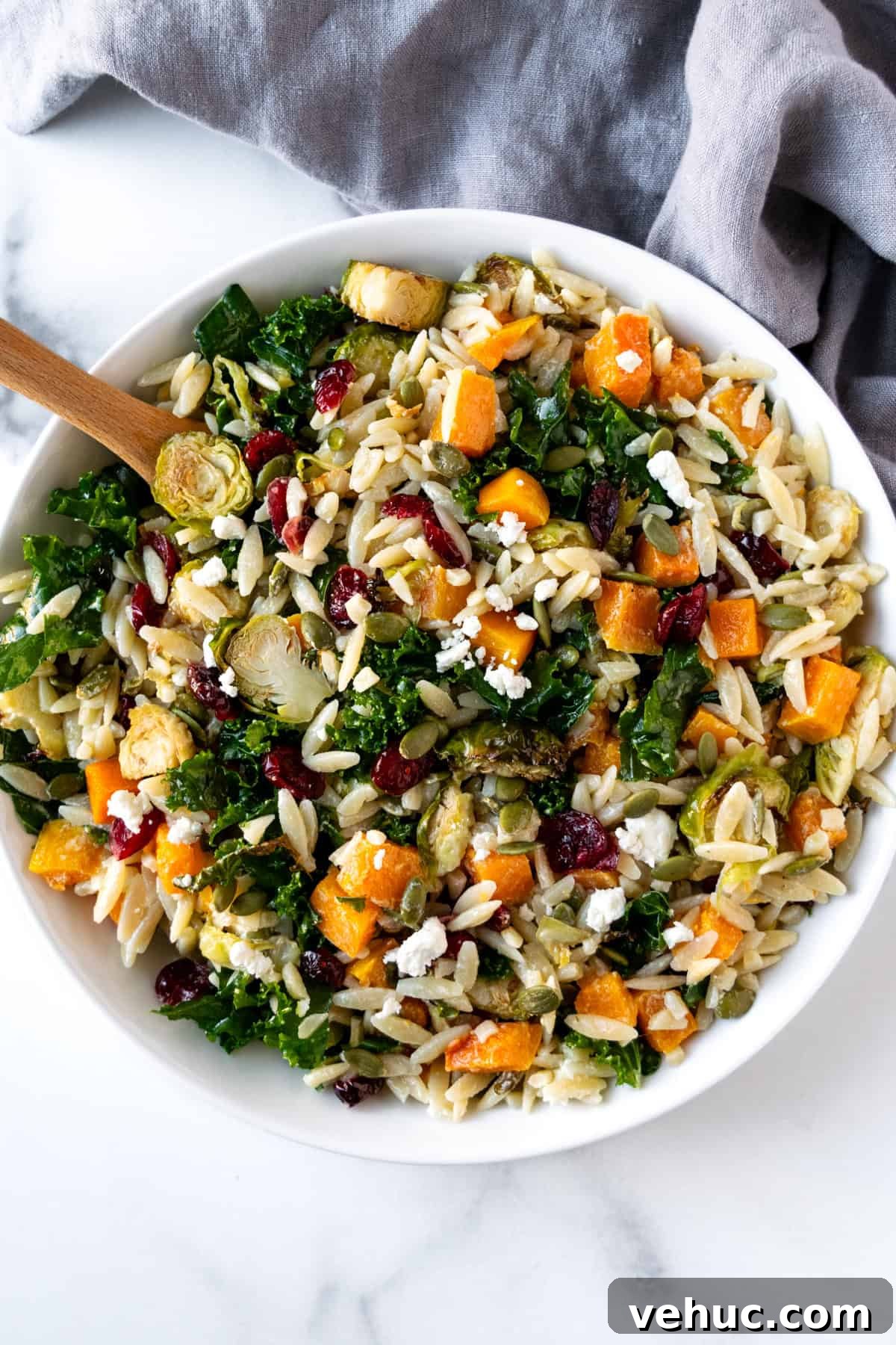 Autumn Harvest Orzo Salad with Roasted Vegetables and Feta 7 Fall Pasta Salad in a white bowl with a wooden spoon.