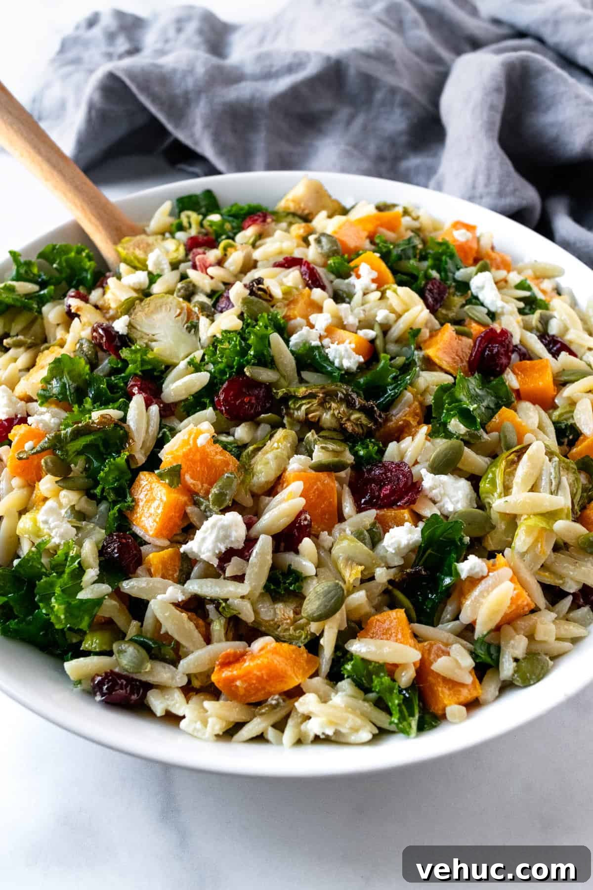 Autumn Harvest Orzo Salad with Roasted Vegetables and Feta 9 Fall Pasta Salad in a white bowl with a serving spoon.