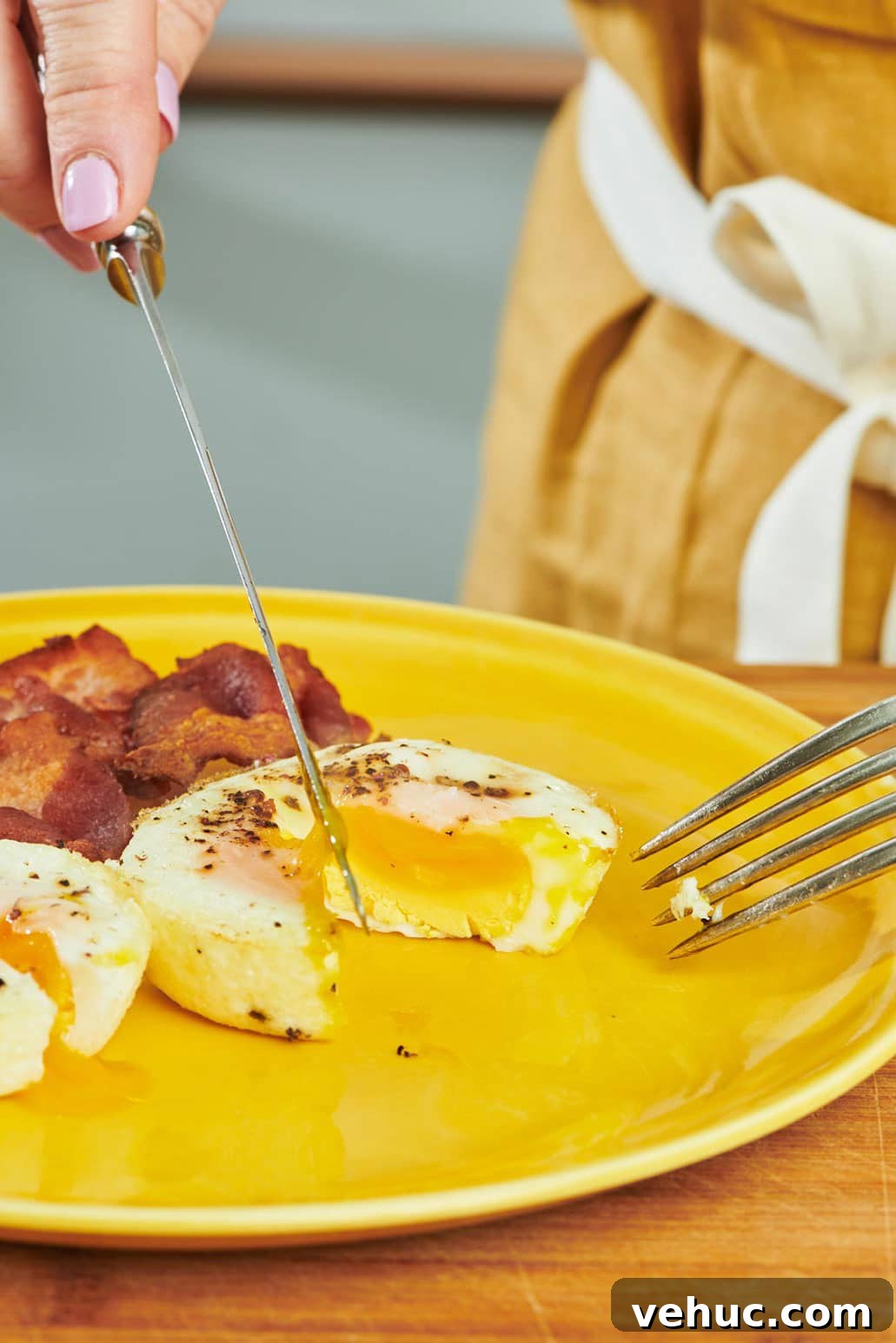 Oven-Baked Eggs: Simple Methods for Perfect Results 2 Slicing oven-baked egg with knife and fork on yellow plate.