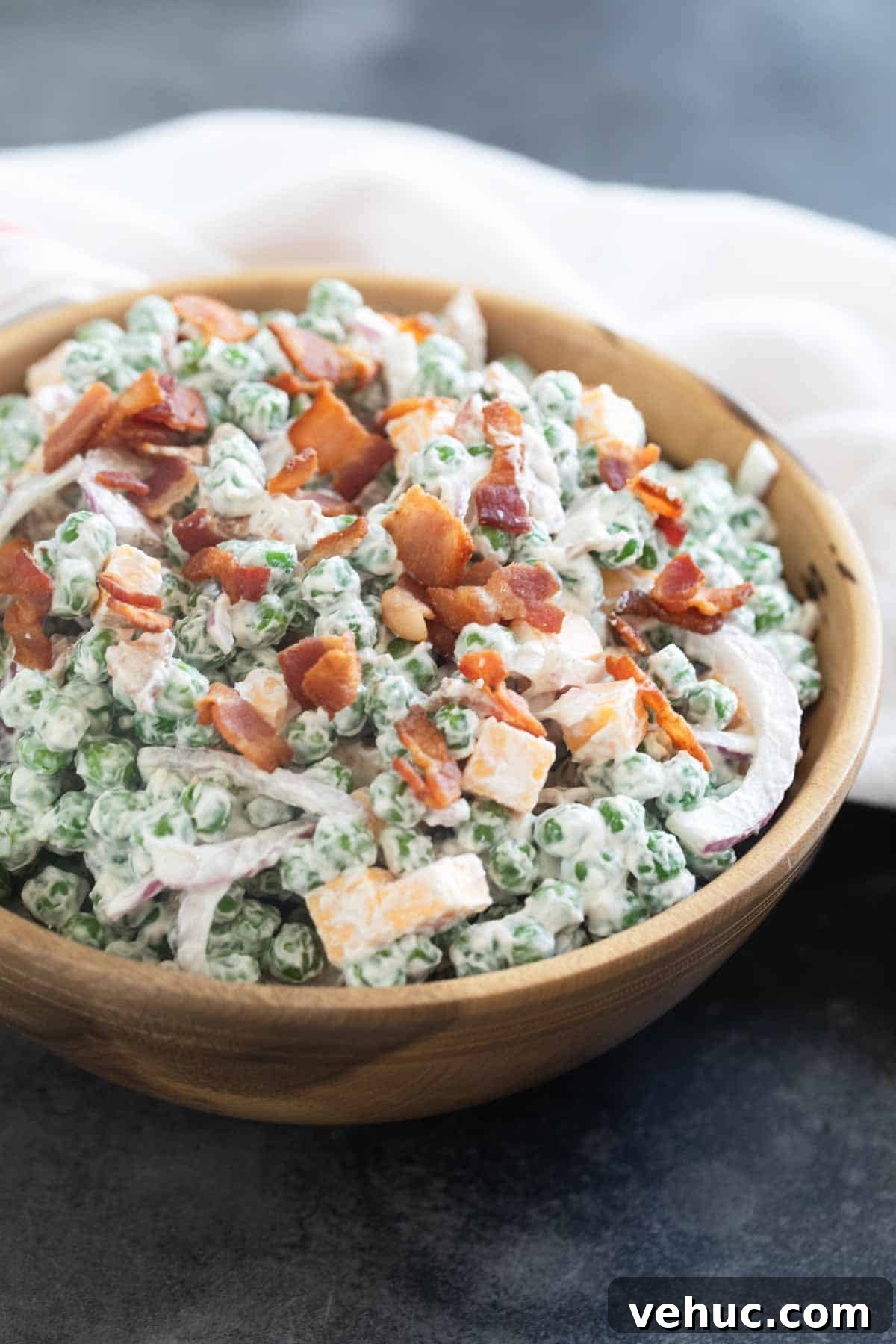 Creamy Pea Salad Recipe with Bacon and Red Onion 6 Pea Salad in a wooden bowl, topped with bacon.