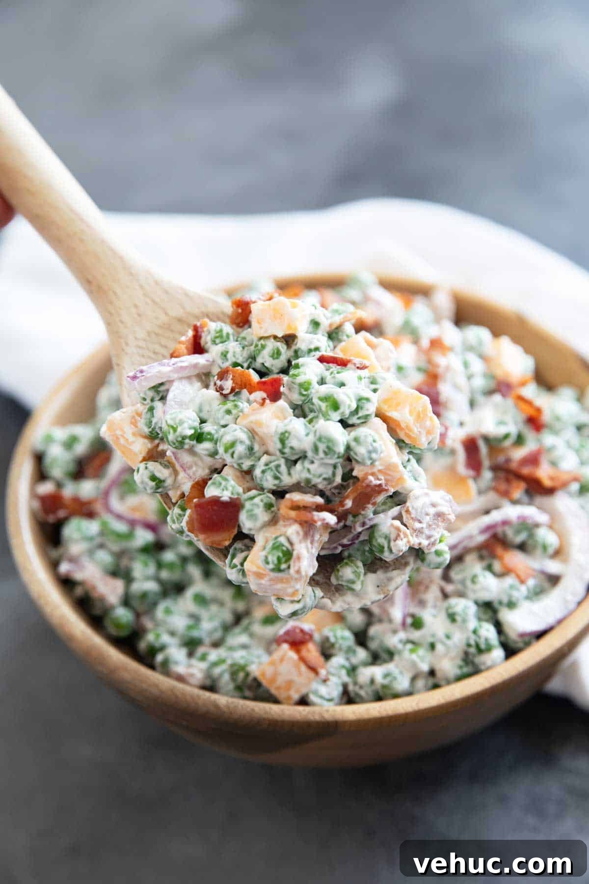 Creamy Pea Salad Recipe with Bacon and Red Onion 7 Large spoonful of pea salad over the bowl of salad.