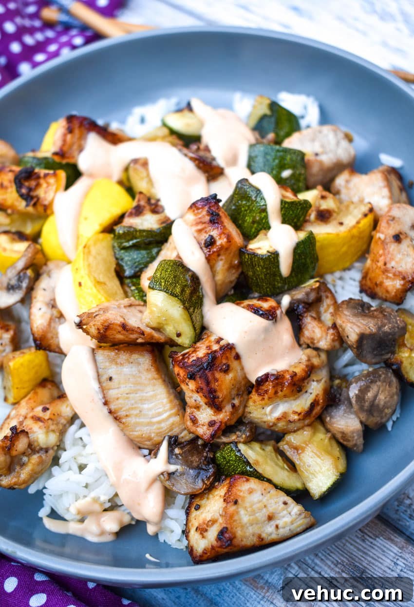 Air Fryer Hibachi-Style Chicken and Vegetables Recipe 2 air fryer hibachi chicken and vegetables over steamed rice and topped with yum yum sauce on a gray plate