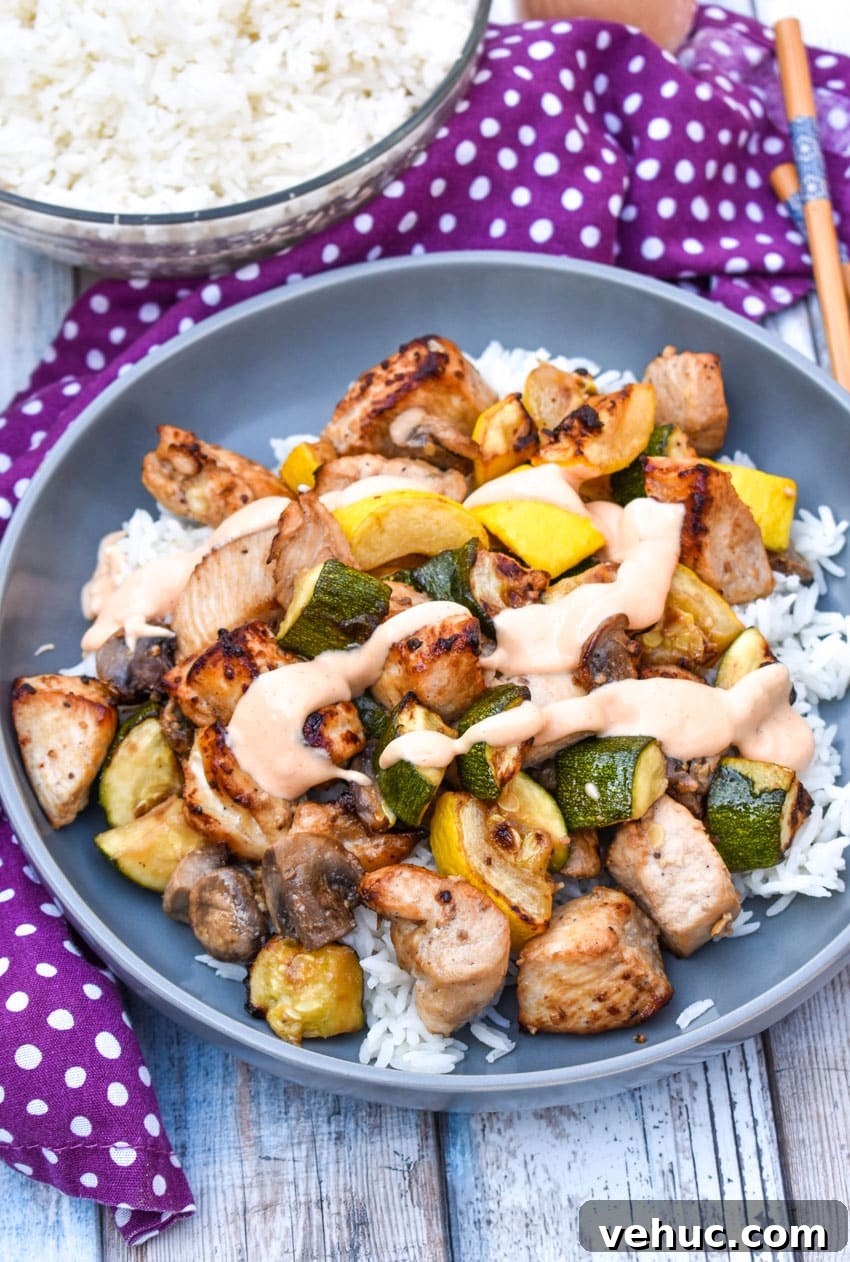 Air Fryer Hibachi-Style Chicken and Vegetables Recipe 3 air fryer hibachi chicken and vegetables over steamed rice and topped with yum yum sauce on a gray plate