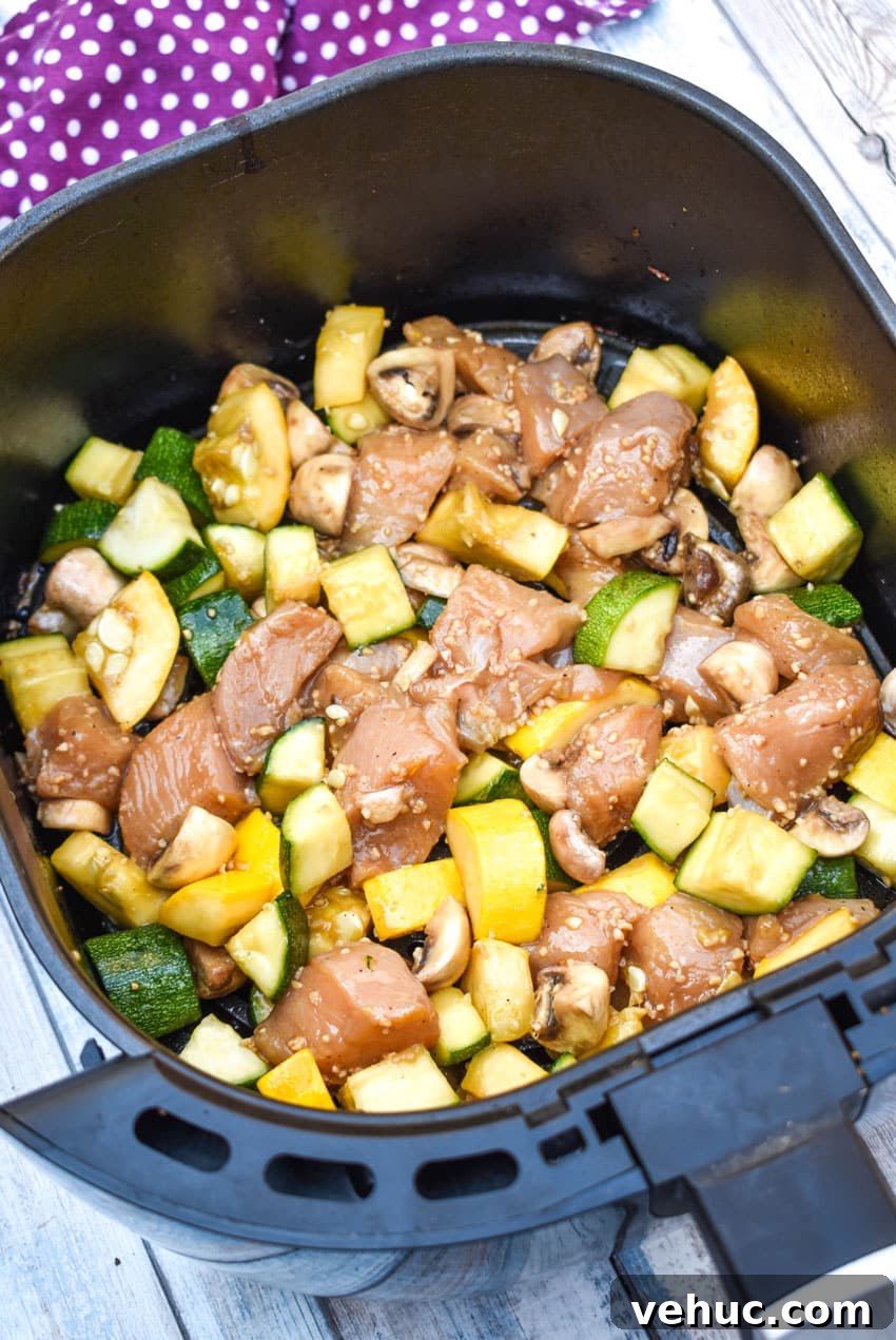 Air Fryer Hibachi-Style Chicken and Vegetables Recipe 5 uncooked air fryer hibachi chicken and vegetables ingredients in an air fryer basket