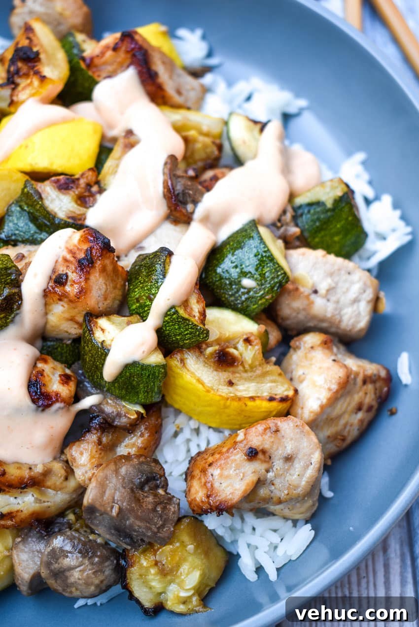 Air Fryer Hibachi-Style Chicken and Vegetables Recipe 9 air fryer hibachi chicken and vegetables over steamed rice and topped with yum yum sauce on a gray plate