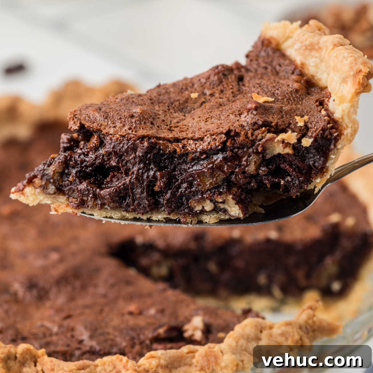 A slice of chocolate pecan pie being lifted out of the pie dish.