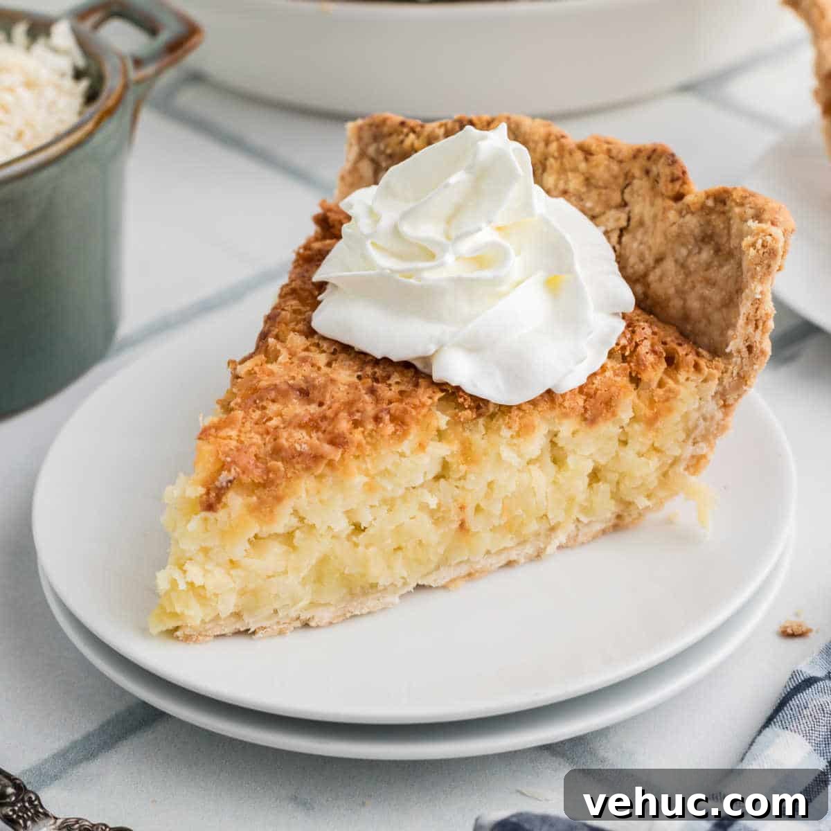 A slice of coconut pie with some cream squirted on top.