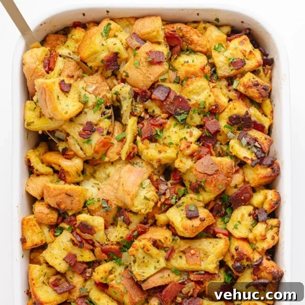 Creamy Cheddar Scalloped Potatoes Recipe 13 Bacon, sage and onion stuffing in a white casserole dish with serving spoon in corner.