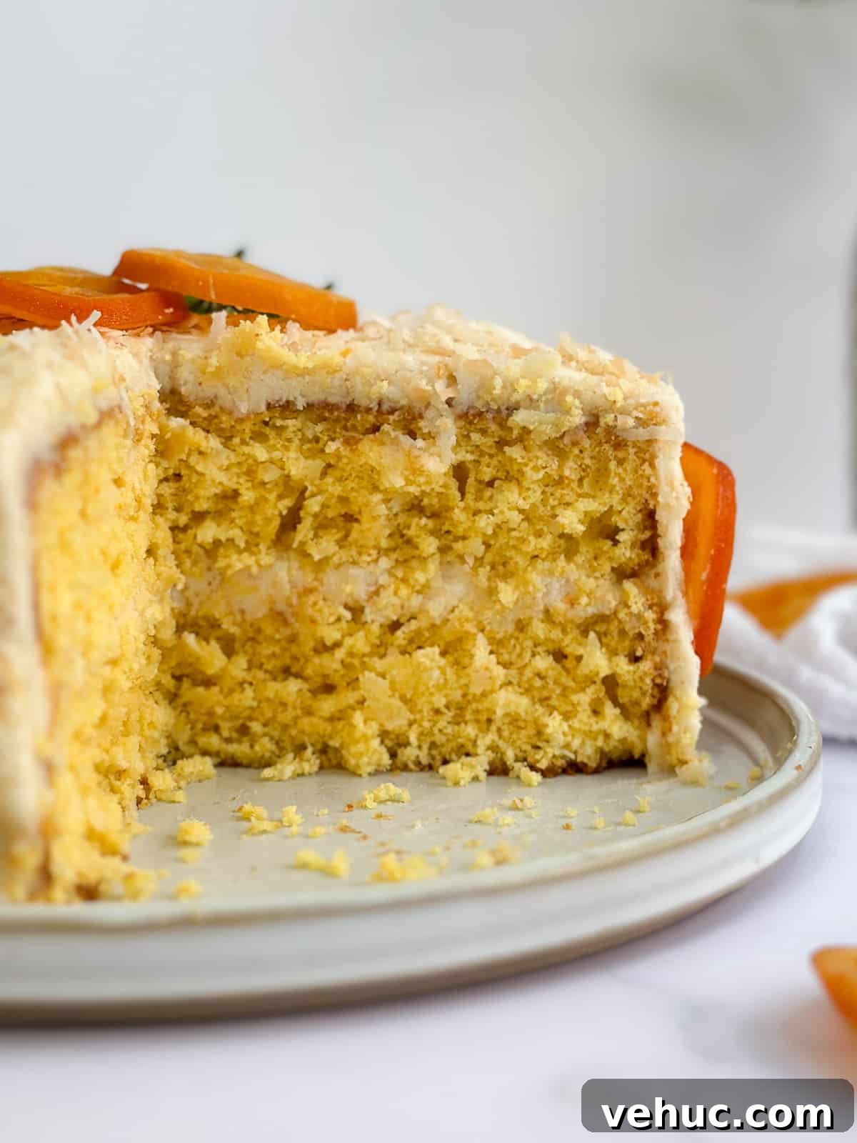Moist Orange Coconut Cake Recipe with Zesty Glaze 18 a huge wedge of cake missing so you can see the inside and the layers.