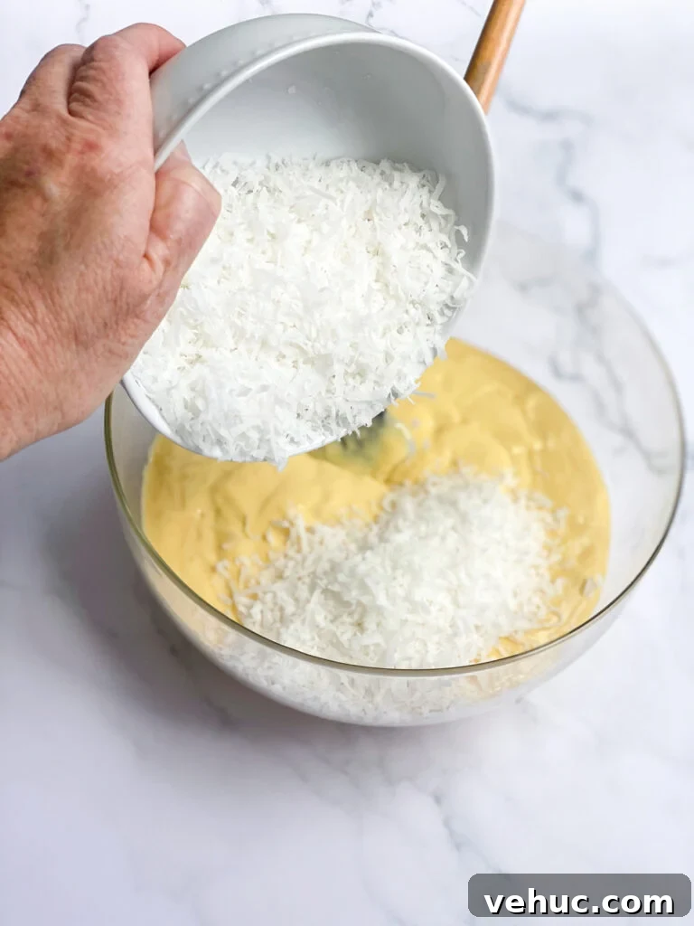 Moist Orange Coconut Cake Recipe with Zesty Glaze 5 adding coconut to batter.