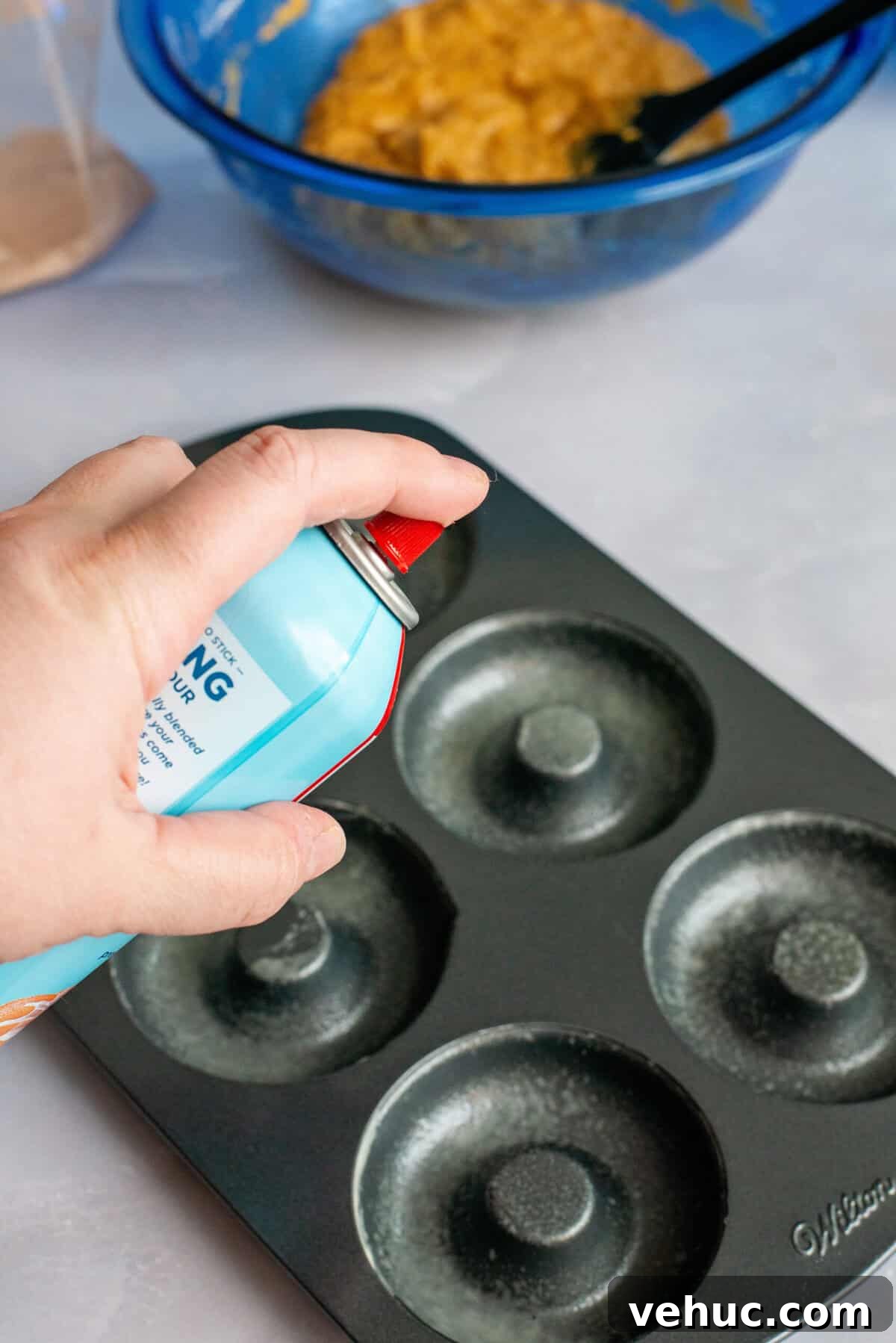 Pumpkin Spice Cake Donuts Recipe — Moist Fall Donut Tutorial 5 Spraying a donut pan with non-stick cooking spray.