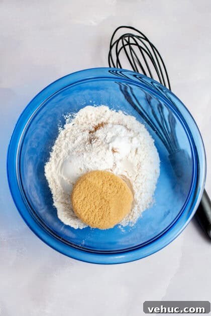 Pumpkin Spice Cake Donuts Recipe — Moist Fall Donut Tutorial 6 Mixing the dry ingredients together in a glass blue mixing bowl.