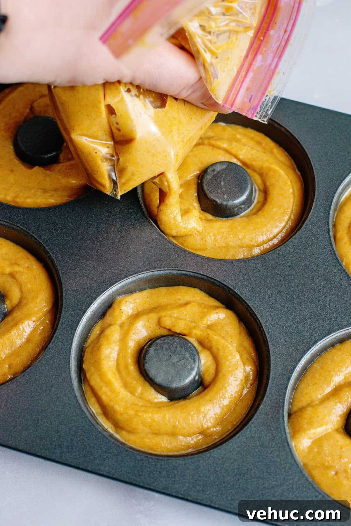 Pumpkin Spice Cake Donuts Recipe — Moist Fall Donut Tutorial 9 Piping donut batter into a donut tin.